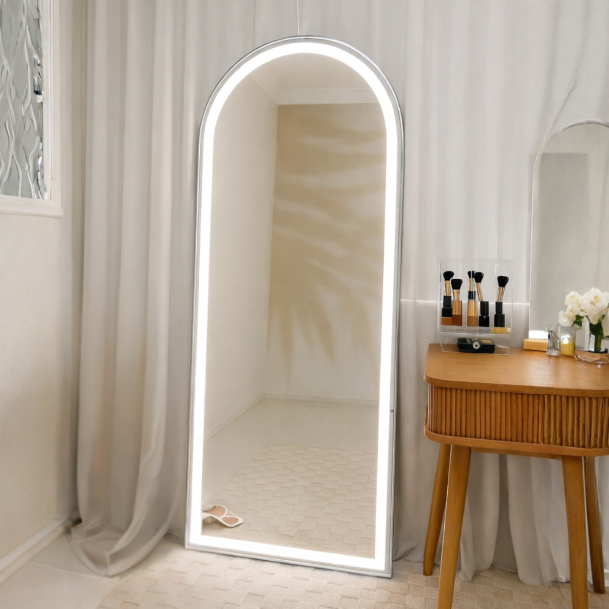Arched LED mirror in a room with a wooden side table and decorative items.